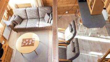 A wooden interior with a sofa, chairs, a small table, and a cabinet.