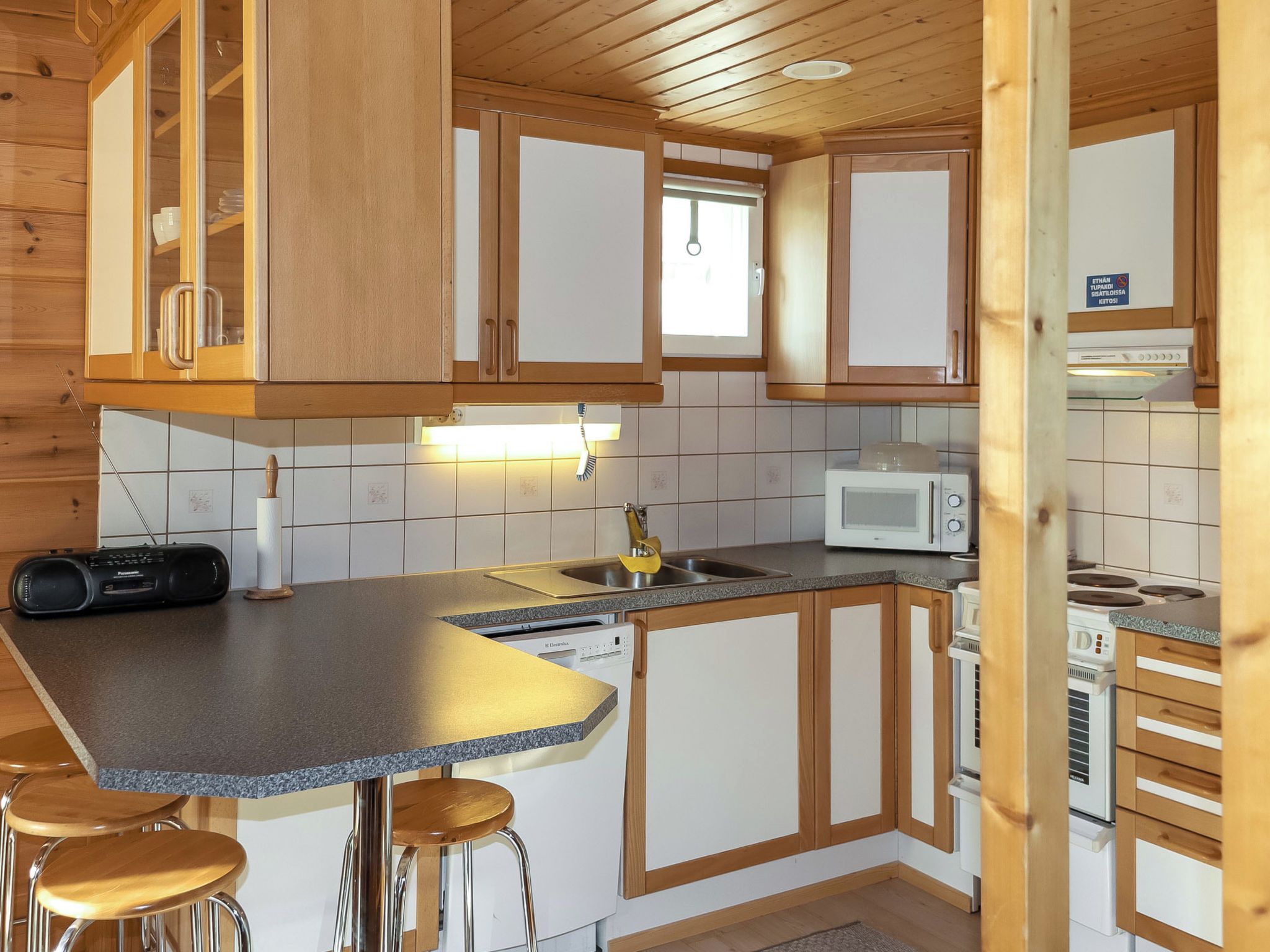 A compact kitchen with wooden cabinets, a microwave, a sink, and a dishwasher.