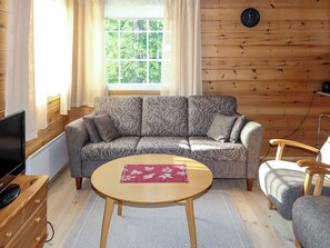 A cozy living room with a sofa, a round coffee table, and a television.