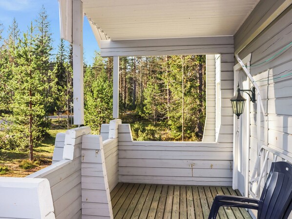 A covered porch with a view of a forest.