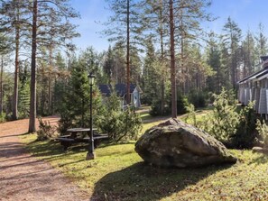 Relax on a natural bench amidst a serene forest setting with a nearby rock and a secluded cluster of trees.