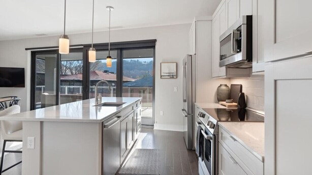 A modern kitchen with a central island, stainless steel appliances, and pendant lighting. - Luxury Condo, Downtown Asheville (Asheville)