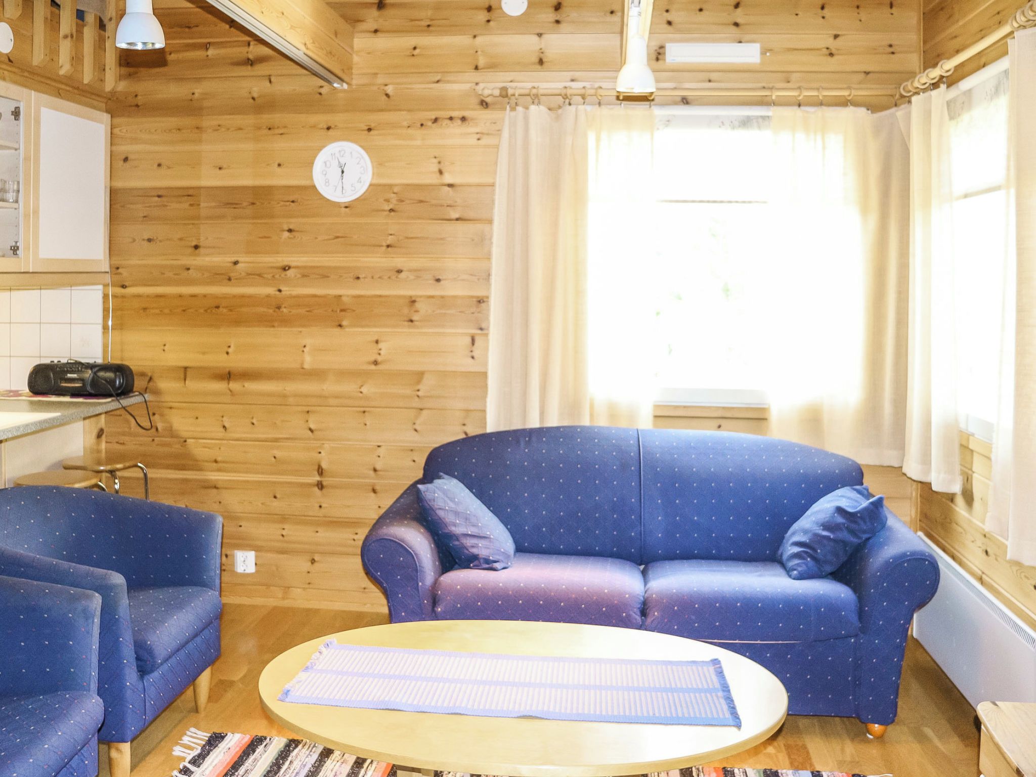 Una habitación acogedora con un sofá azul, una mesita pequeña y un techo de madera.