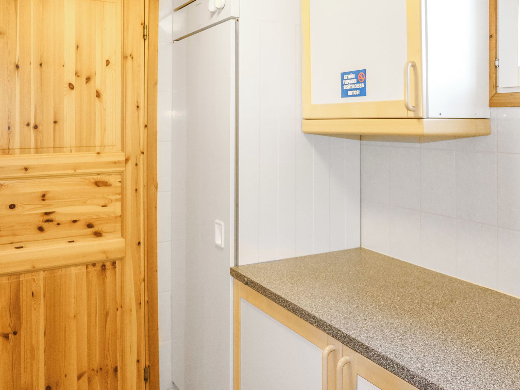 A kitchen with a wooden cabinet, a white refrigerator, and a granite countertop.