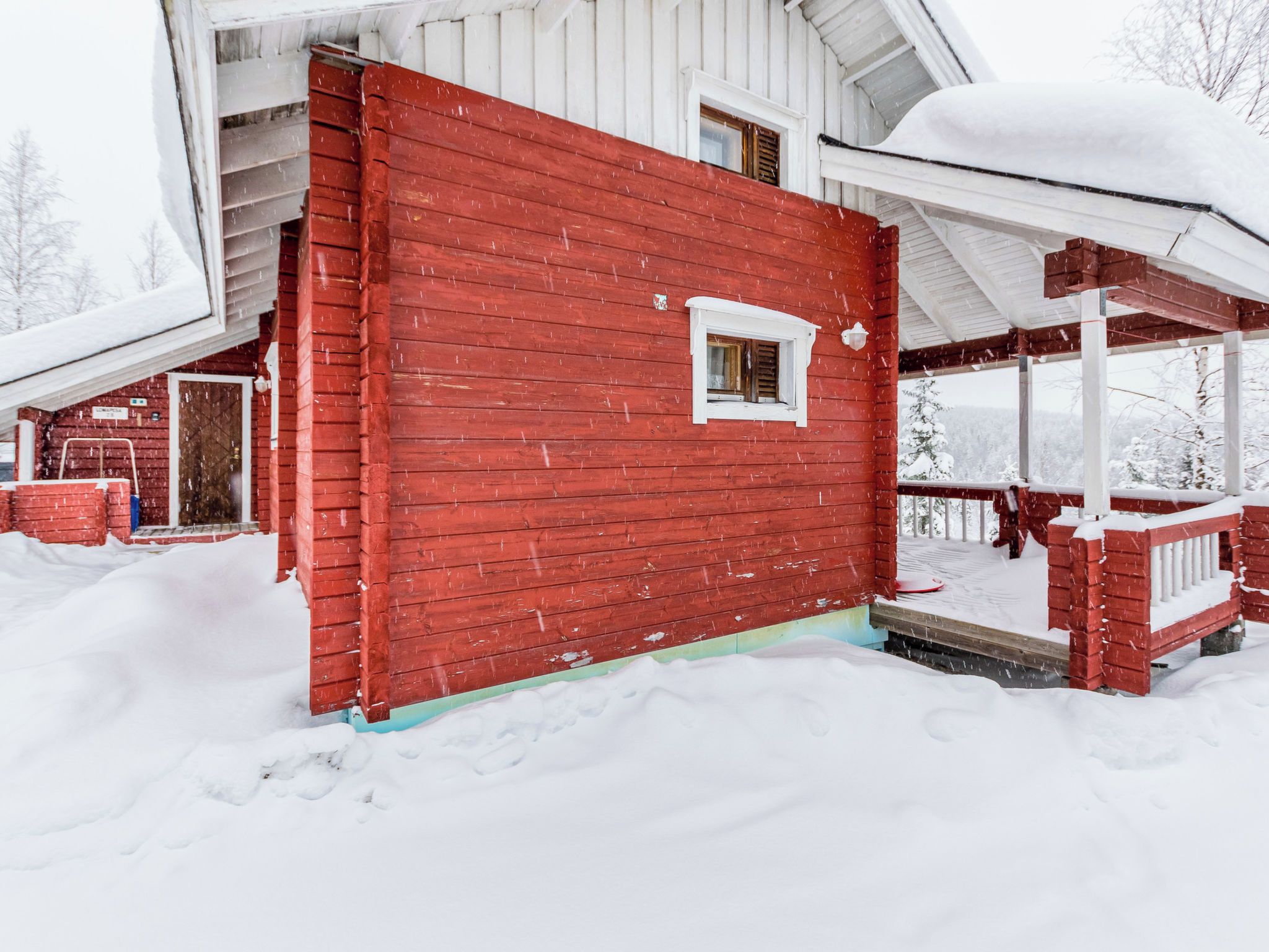 A red wooden house with a porch and a window.