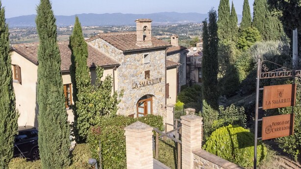 A stone building with "LA SMARRITA" signage, surrounded by greenery and a view of distant hills. - Stunning private villa for 10 guests with hot tub, WIFI, A/C, private pool, TV and terrace (Lucignano)