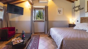 A bedroom with a bed, a TV mounted on the wall, a window with curtains, a red chair, a small table with snacks, and a 'always together' sign on the wall. - Stunning private villa for 10 guests with hot tub, WIFI, A/C, private pool, TV and terrace (Lucignano)