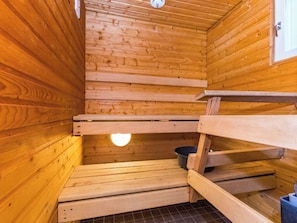 Una sauna de madera con bancos y una pequeña cuenca.