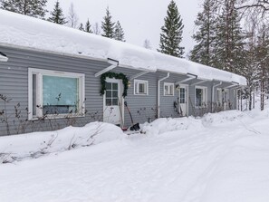 Une rangée de cabanes aux toits enneigés, se dressant au milieu d’un paysage hivernal.