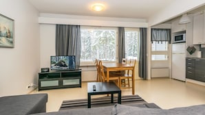 Ein modernes Wohnzimmer mit einer Couch, einem Fernseher und einem Essbereich mit Tisch und Stühlen.