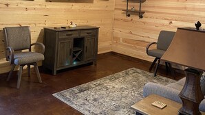 Ein rustikaler Innenraum mit Holzwänden, einem Deckenventilator, einem an der Wand montierten Fernseher, einem Hirschgeweih als Dekoration und einem Schreibtisch mit einer Lampe.