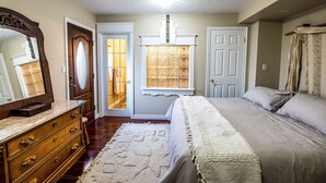 Une chambre à coucher comprenant un lit, une commode, un miroir et une fenêtre donnant sur l’extérieur.