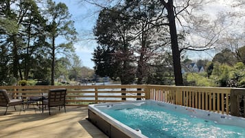Relax on a serene deck surrounded by lush greenery and a tranquil body of water.