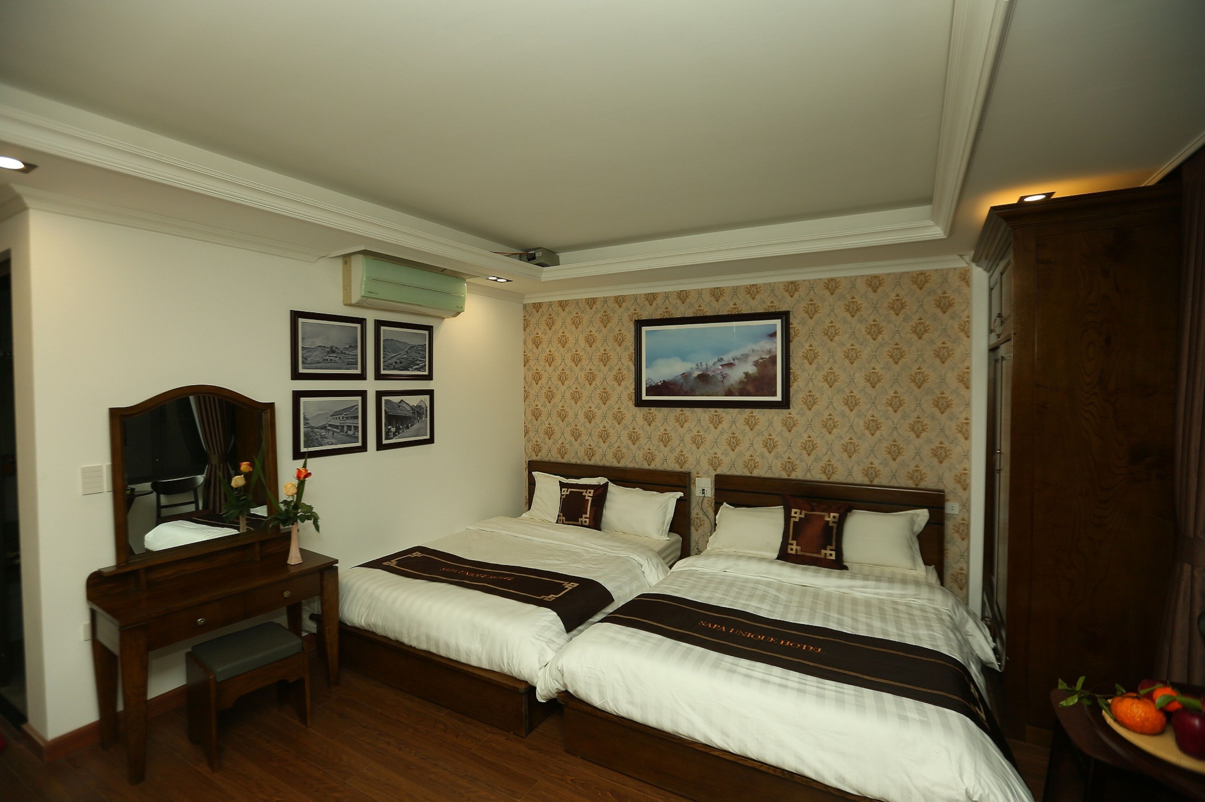 A hotel room with two beds, a desk with a mirror, and a dresser.