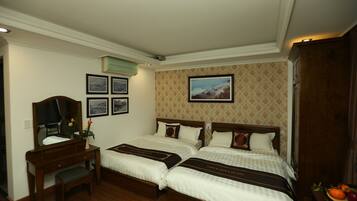 A hotel room with two beds, a desk with a mirror, and a dresser.
