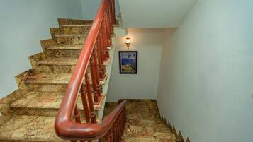 A staircase with a red handrail, granite steps, and a framed picture on the wall.