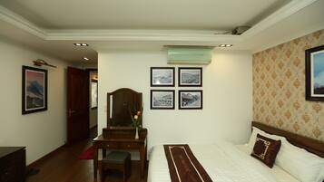 A hotel room with a bed, a desk, and a chair. There are four framed pictures on the wall.