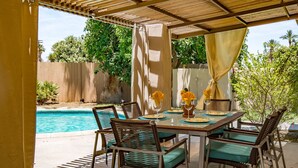 An outdoor patio with a pool, a dining table with chairs, and a pergola. - ATOMIC-MOD HOUSE in prime Palm Desert/next to El Paseo! (Palm Desert)