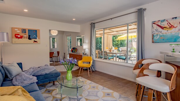 A modern living room with a blue sofa, yellow armchairs, and a glass coffee table. - ATOMIC-MOD HOUSE in prime Palm Desert/next to El Paseo! (Palm Desert)