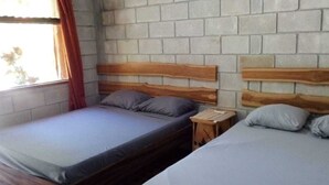 Een kamer met twee bedden, elk met een houten hoofdbord en grijze beddengoed.