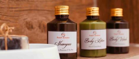 Three bottles of PamV Estates body care products on a wooden shelf.