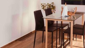 Un'area pranzo con tavolo in vetro, sedie nere e un quadro di un albero appeso al muro.