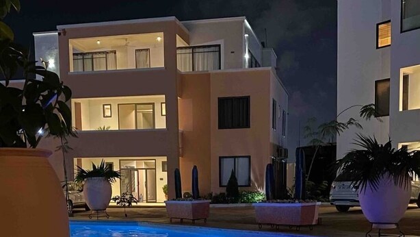Un hotel moderno con piscina, diversi balconi e piante in vaso.