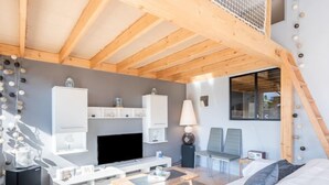Une chambre d’hôtel moderne dotée d’un plafond en bois, d’un téléviseur à écran plat, d’un lit, d’un bureau et d’une chaise.