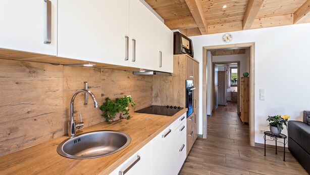 A modern kitchen with wooden cabinets, a stainless steel sink, and a wooden countertop.