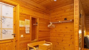 Ein Holzhäuschen-Zimmer mit Holzschreibtisch, Stuhl und Kleiderständer.