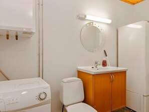 Bathroom features a toilet, sink, and cabinet, with a heater and refrigerator nearby.