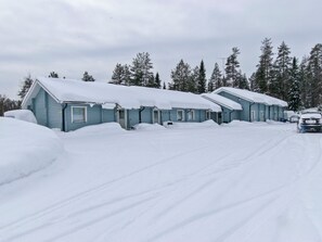 Una fila di cabine blu con tetti imbiancati dalla neve, immerse in un paesaggio innevato e una fitta foresta.