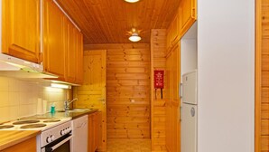 Eine kleine Küche mit Holzausstattung, einem Herd, einer Spüle und einem Kühlschrank.