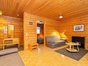 Een houten interieur met een bank, een bijzettafeltje, een houten bankje en een open haard.
