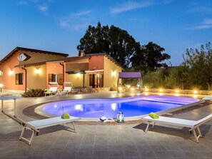 Une maison avec une piscine, des chaises longues et un patio couvert.