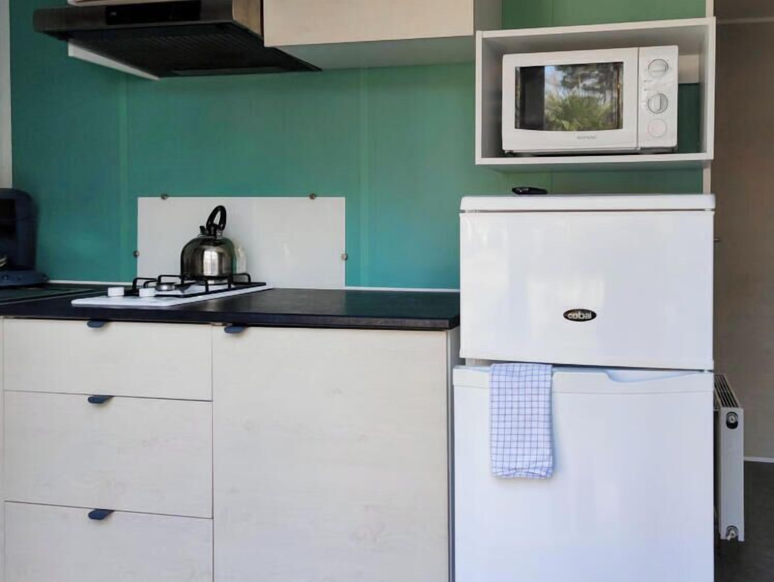 Cocina compacta con estufa a gas, hervidor, microondas y refrigerador.