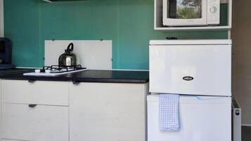 Cocina compacta con estufa a gas, hervidor, microondas y refrigerador.