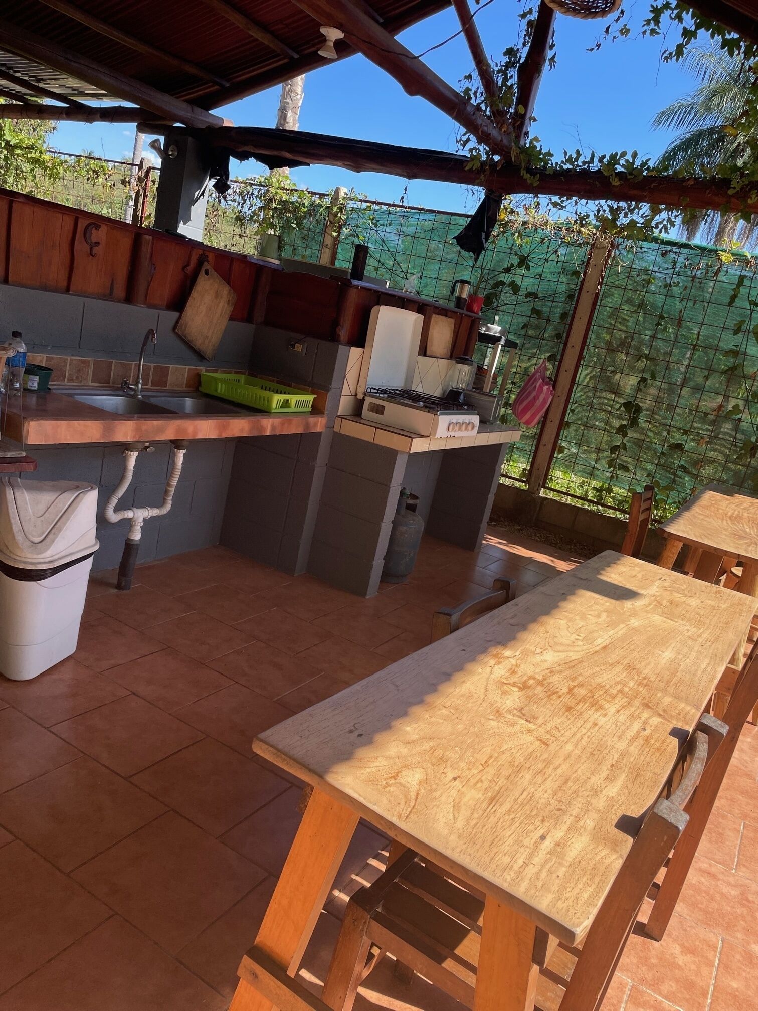 An outdoor kitchen with a sink, stove, and wooden table.