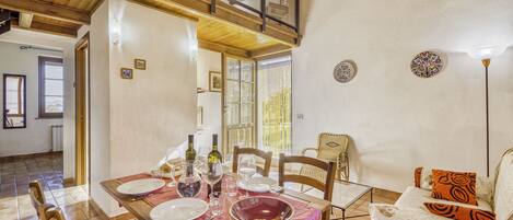 A dining area with a wooden table set for four, surrounded by chairs. There are decorative plates and a bowl on the table.