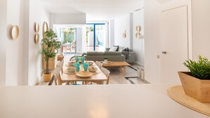 A modern living space with a dining area, a sofa, and a kitchen.