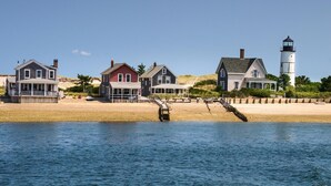 Een kustgebied met verschillende huizen en een vuurtoren. Huizen staan op zandgrond, dichtbij het water.