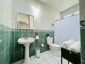 A bathroom with a pedestal sink, toilet, and shower curtain. - Located on the SouthWest Side of Puerto Rico (cabo rojo)