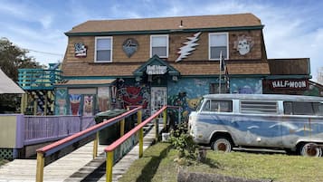A building with a mural, a vintage van, and a staircase leading to a porch.