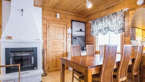 Ein Holzinnenraum mit Kamin, Esstisch und Stühlen.