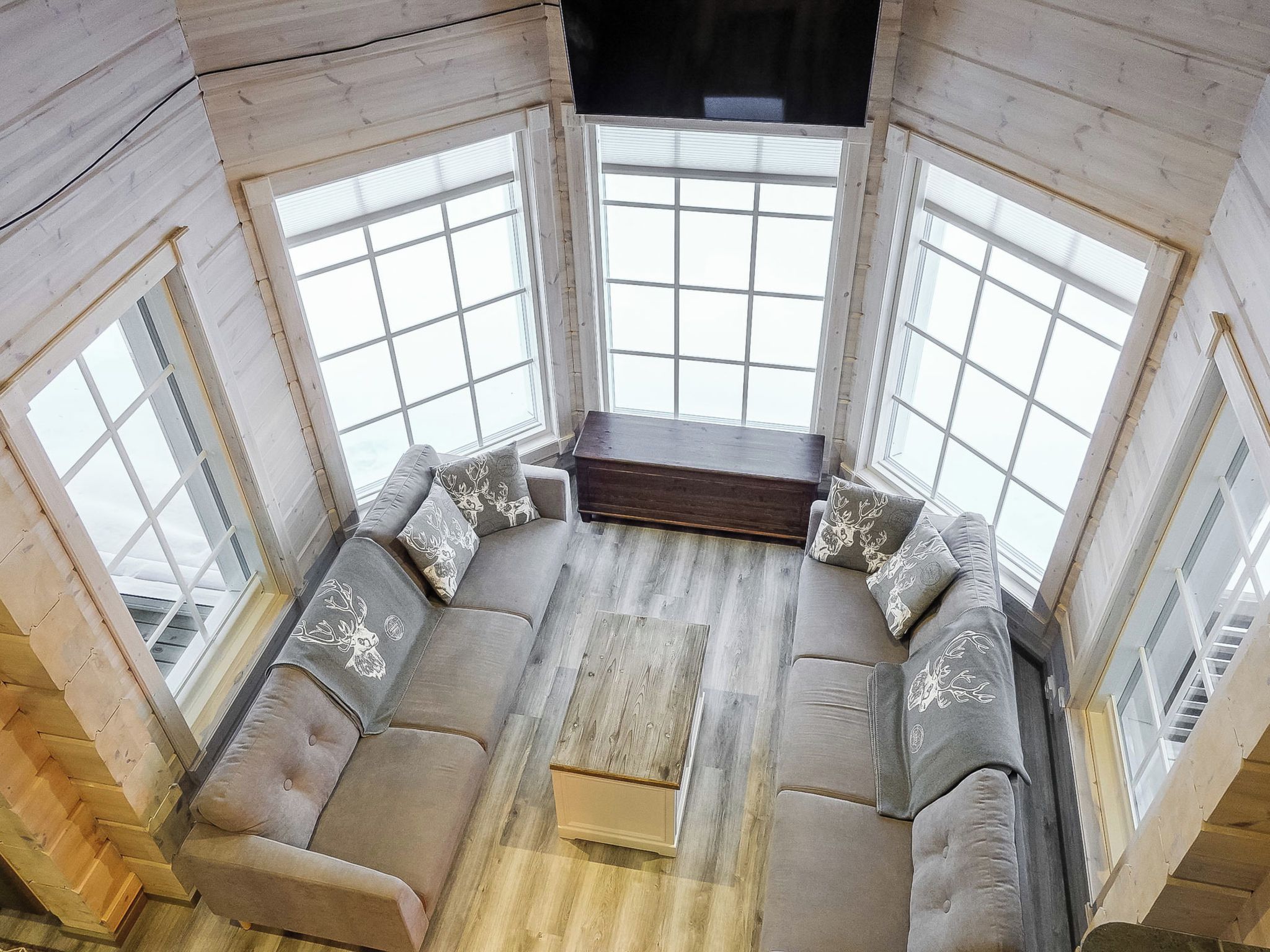 Une pièce d’angle avec un plancher en bois, un ensemble de meubles de salon et de grandes fenêtres.