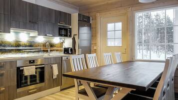Una cocina moderna con una mesa y sillas de madera, horno empotrado y un ventanal grande.