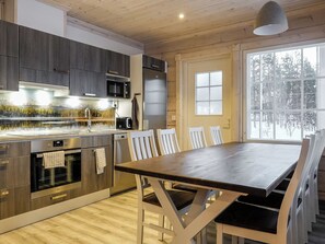 Una cocina moderna con una mesa y sillas de madera, horno empotrado y un ventanal grande.
