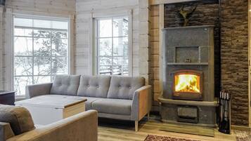 Una sala de estar acogedora con chimenea de piedra, un sofá gris y una mesita de centro.