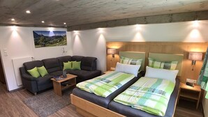A bedroom with a wooden bed, two bedside tables, a sofa, and a view of a mountainous landscape.