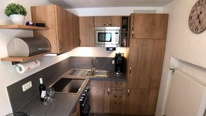 A compact kitchen with wooden cabinets, a stainless steel sink, a microwave, and a coffee maker.